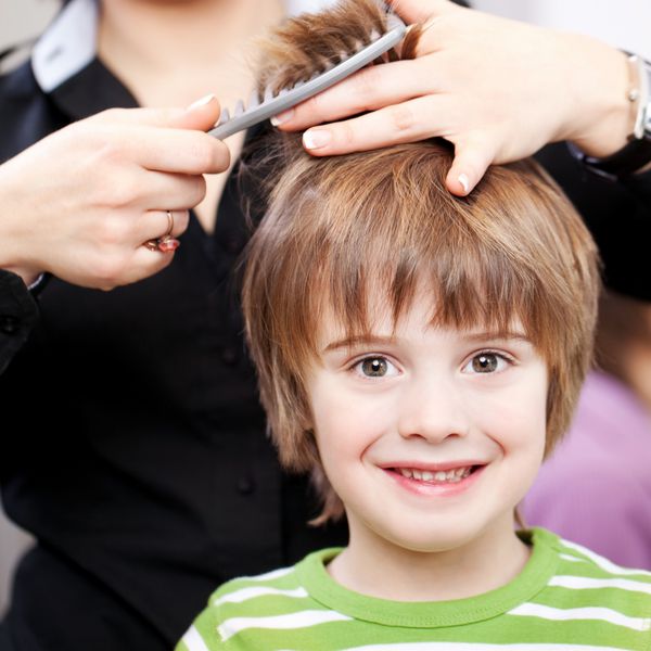 کودک خردسال زیبا با چشمان درشت رسا در آرایشگاه که موهایش را کوتاه کرده است