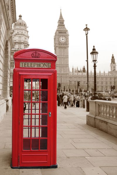 یک باجه تلفن قرمز سنتی در لندن با بیگ بن در پس‌زمینه قهوه‌ای فوکوس کوتاه پس‌زمینه تار است