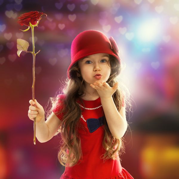 مردم مفهوم شادی دختر کوچولوی شاد با رز با لباس قرمز دستش را ببوس می فرستد