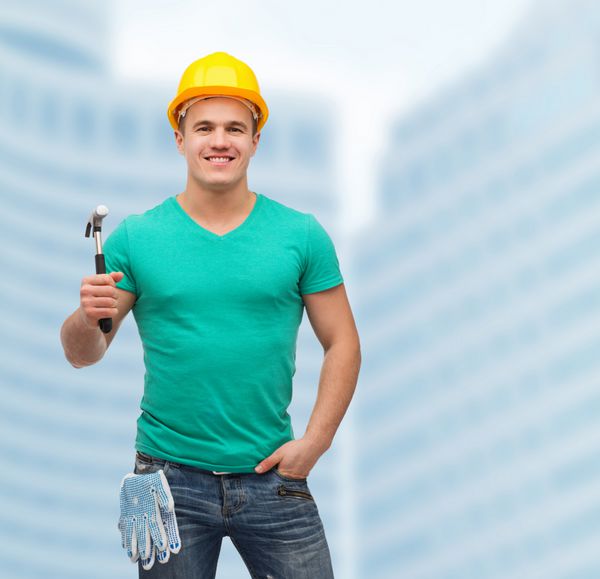 مفهوم تعمیر ساخت و نگهداری - کارگر دستی مرد خندان در کلاه ایمنی با چکش