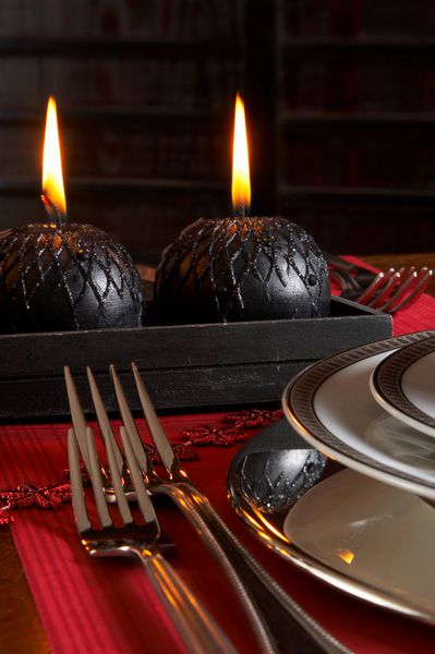 جزئیات میز شام کریسمس با دستمال های قرمز و شمع های مشکی