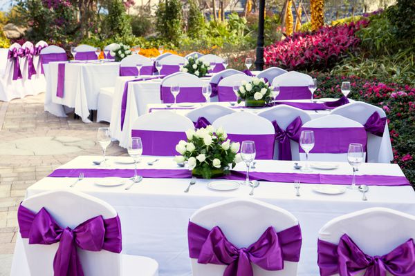میزهای فضای باز با بشقاب های سرو شده و لیوان های شراب در باغ