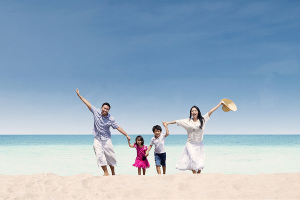 خانواده آسیایی شاد در حال دویدن در ساحل