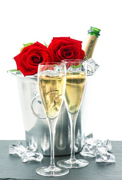 دو لیوان بطری شامپاین و رز قرمز چیدمان جشن با شراب گازدار و گل