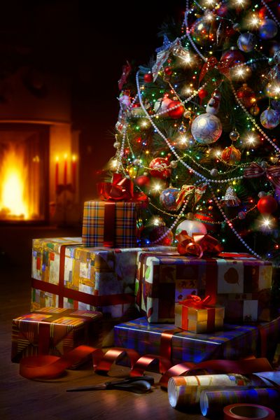 جعبه های هنری درخت کریسمس و هدیه کریسمس در فضای داخلی با یک شومینه
