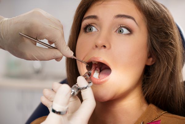 دندانپزشکی که به بیمار زن ترسیده داروی بی حسی تزریق می کند