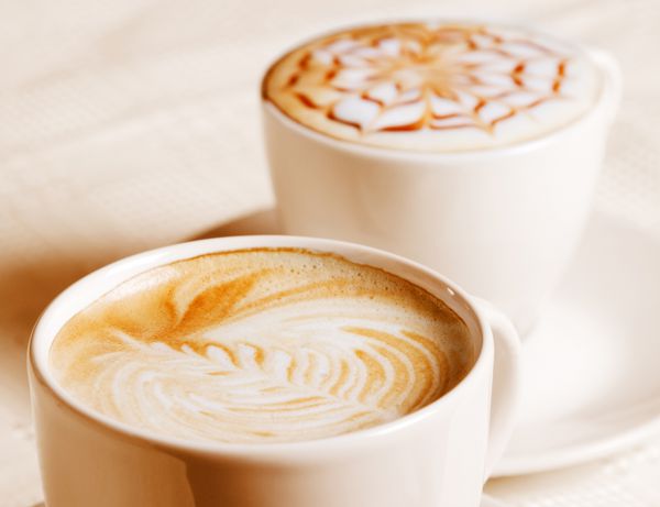 فنجان قهوه با تزئین کرم هنری جدا شده در زمینه سفید