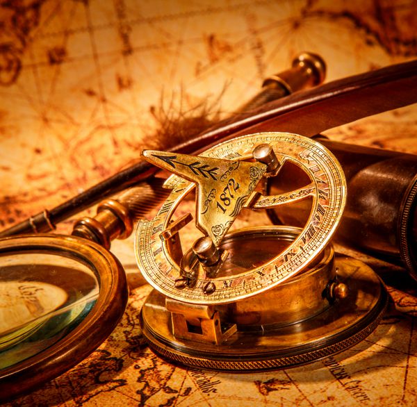 قطب نما قدیمی خودکار غاز جاسوسی و یک ساعت جیبی که روی یک نقشه قدیمی قرار دارد