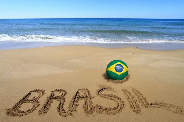 توپ فوتبال با پرچم برزیل و کلمه برزیل روی ساحل نوشته شده است