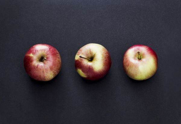 سه سیب در پس زمینه تیره