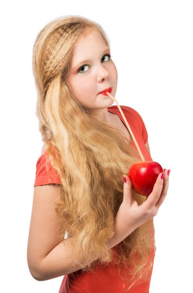 دختر نوجوان جذاب با تی شرت نارنجی که یک سیب قرمز در دست دارد و به دوربین نگاه می کند نمای نزدیک روی پس‌زمینه جدا شده سفید