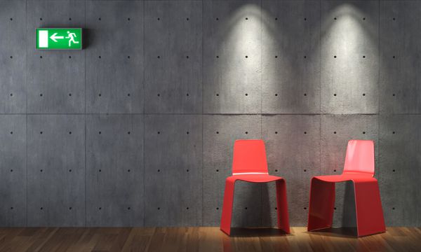 طراحی داخلی مدرن دو صندلی قرمز روی دیوار بتنی با علامت خروج اضطراری