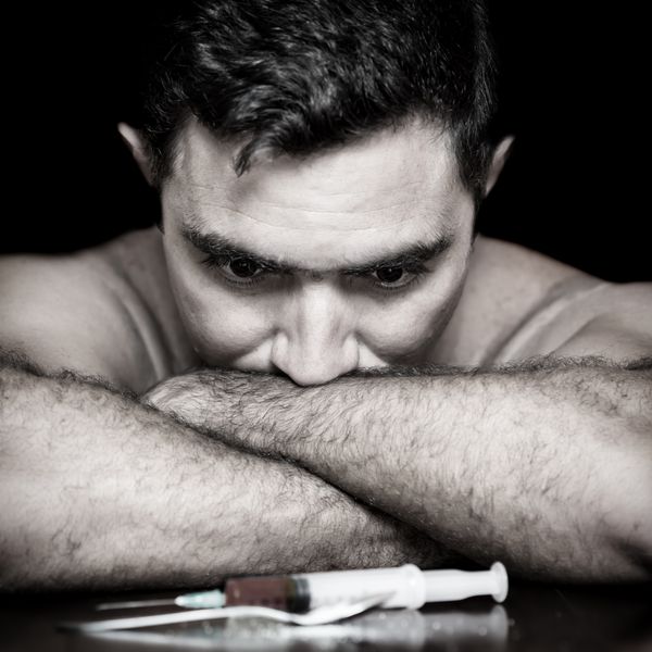 تصویر گرانج از یک معتاد افسرده که به سرنگ و مواد مخدر نگاه می کند