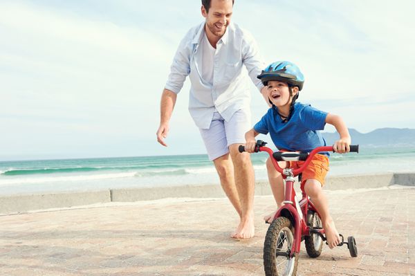 پدر و پسر دوچرخه سواری را در ساحل یاد می گیرند و با هم سرگرم می شوند