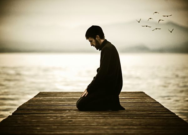 مرد مسلمانی که ماه رمضان را روزه می گیرد و روی دریاچه زیبا نماز می خواند عکس ظاهر قدیمی همراه با نویز اضافه شده