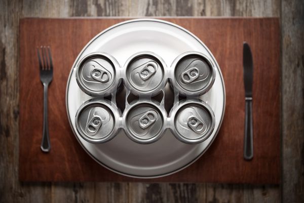 تصویر مفهومی نشان دهنده اعتیاد به الکل به روشی خنده دار با استفاده از یک بسته شش عددی قوطی آبجو برای شام