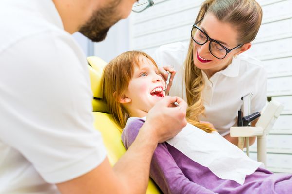 دندانپزشک در حال درمان دختر در جراحی دندان