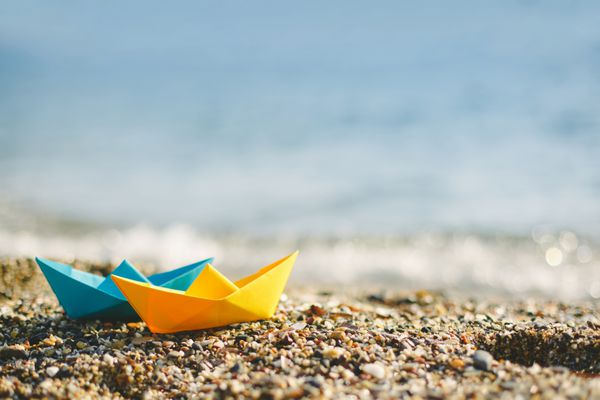 قایق های کاغذی آبی و زرد در ساحل در فضای باز