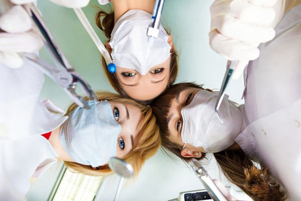 نمایی از پزشکان دندانپزشکان در دست داشتن ابزار جراحی توسط بیمار پس از عمل بر روی زمینه لامپ سقف بیمارستان بیمار ویزیت بخش مراقبت های ویژه بستری اورژانسی
