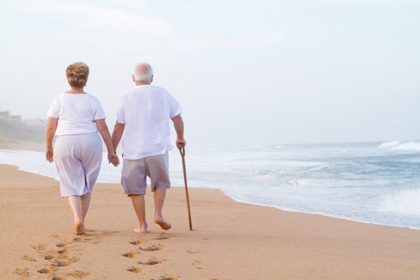 زوج سالخورده دست در دست هم که در ساحل قدم می زنند