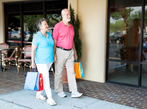 زوج سالخورده با هم در یک مرکز خرید در فضای باز خرید می کنند