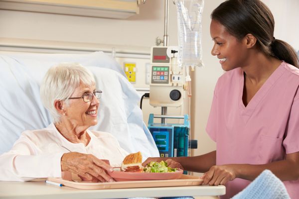 پرستار غذای بیمار زن سالمند در تخت بیمارستان