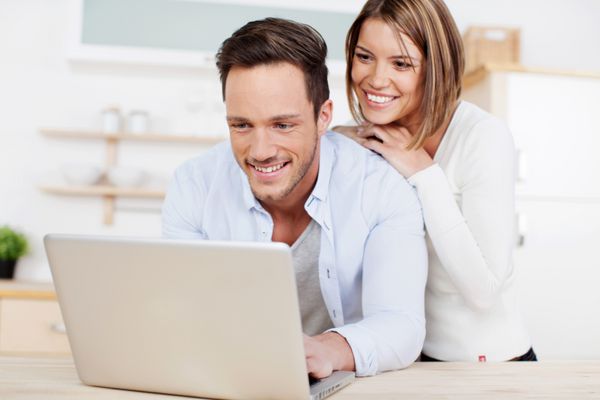 زوج خندان در حال گشت و گذار در اینترنت با لپ تاپ