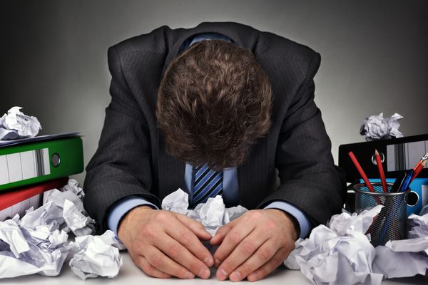 تاجر بیش از حد کار افسرده و خسته پشت میزش با انبوهی از کار یا مفهومی برای سرخوردگی استرس و مانع نویسندگان