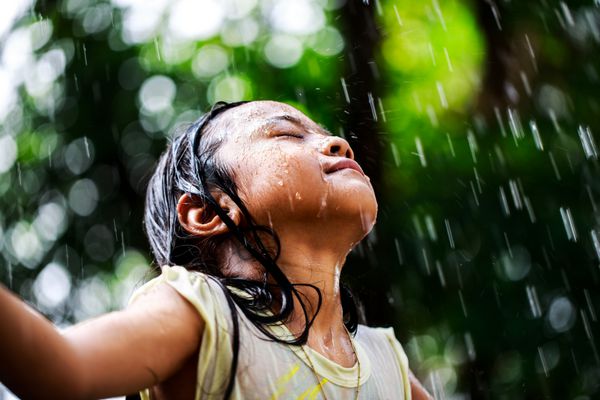 دختر کوچک نزدیک در باران تابستانی