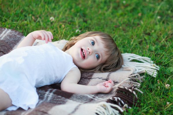دختر کوچک شادی که روی پتو دراز کشیده است