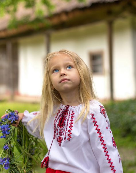 دختر کوچک اوکراینی در حال تماشای زاغی و حلقه گل های خود را در دست دارد