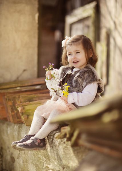 پرتره در فضای باز از دختر کوچک بامزه ای که روی سقف قدیمی نشسته است