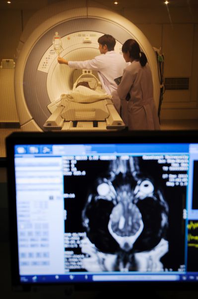 دکتر دامپزشکی که در اتاق اسکنر MRI با پیش زمینه مانیتور کار می کند
