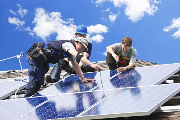 کارگرانی که پنل های خورشیدی فتوولتائیک انرژی جایگزین را روی پشت بام نصب می کنند