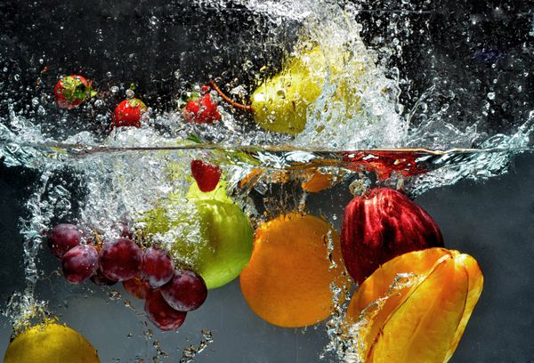 پاشیدن میوه روی آب میوه و سبزیجات تازه در حال غوطه ور شدن در زیر آب تیراندازی می شوند تصویری از شستن غذا قبل از تبدیل شدن به یک غذای سالم و طبیعی