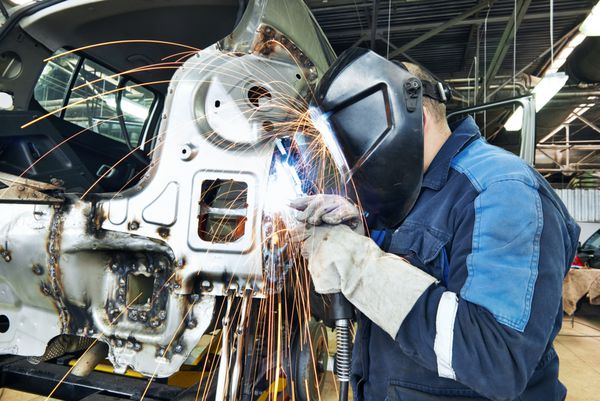 کارگر تعمیرکار حرفه ای در صنعت خودرو جوش ماشین بدنه فلزی با جرقه