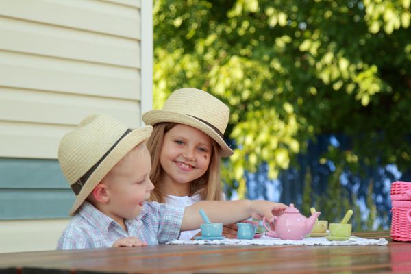 کودکان کوچولو شاد قفقازی در حال بازی با ظروف کودکان در حیاط بیرون از منزل