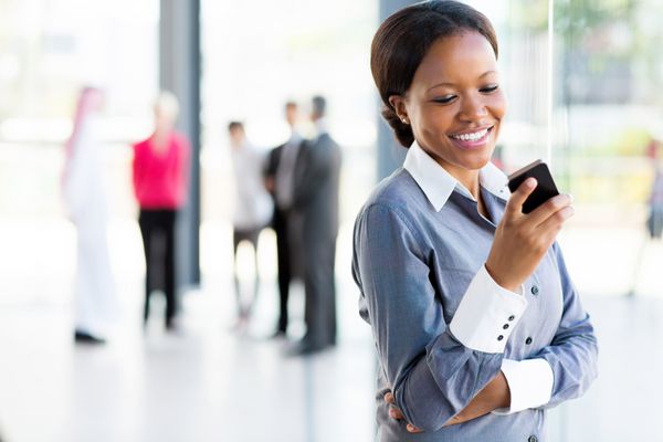 زن حرفه ای آفریقایی آمریکایی شاد با استفاده از تلفن همراه