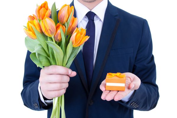 پیشنهاد - مردی که جعبه هدیه با حلقه ازدواج و گل های جدا شده در پس زمینه سفید در دست دارد