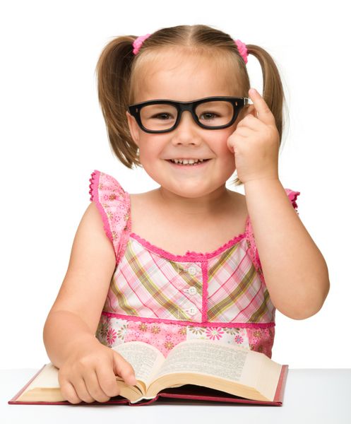دختر کوچک ناز با عینک در حال ورق زدن صفحات یک کتاب جدا شده روی سفید است