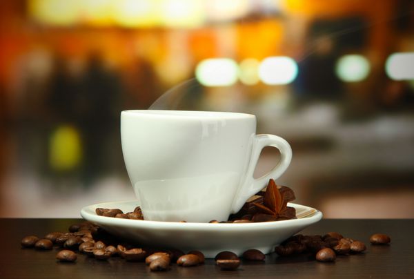 فنجان قهوه با دانه های روی میز در کافه