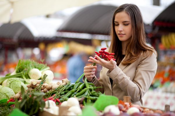 زن جوان در حال خرید فلفل قرمز تند از بازار