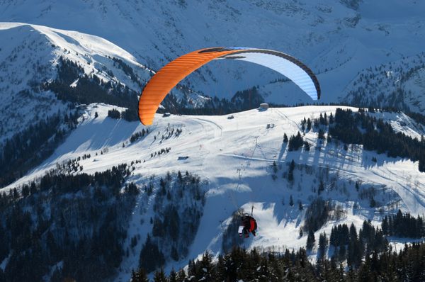 چترباز در حال پرواز بر فراز دامنه های پوشیده از برف در پیست اسکی Chamonix در کوه های آلپ زمستانی است