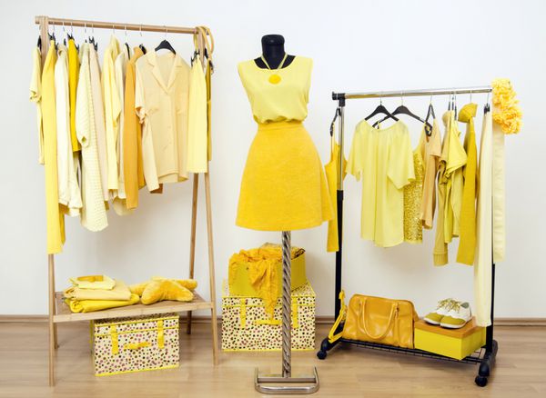 کمد لباس با لباس های زرد چیده شده روی چوب لباسی و لباس روی مانکن کمد لباس پر از تمام سایه های زرد لباس کفش و لوازم جانبی