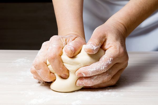 دست در حال ورز دادن خمیر