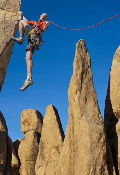 کوهنورد برای گرفتن بعدی خود در لبه یک صخره چالش برانگیز تلاش می کند