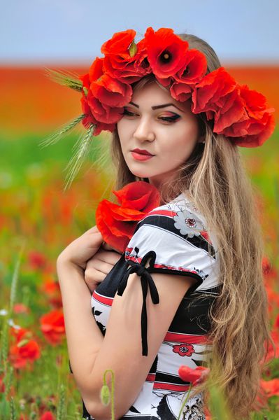 زن جوان زیبا در مزرعه خشخاش قرمز روشن پرتره تابستانی