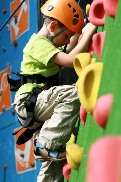 کودک در حال بالا رفتن از دیوار در یک مرکز کوهنوردی در فضای باز