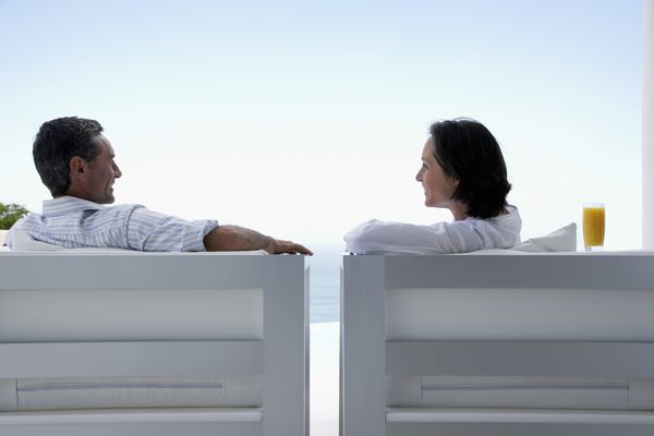 زن و شوهر در حال صحبت کردن نشستن روی صندلی های استراحت در فضای باز