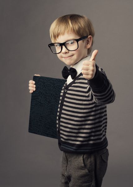 کودک باهوش پسر کوچک با عینک که کتاب خالی گواهی کارت آگهی آموزش مدرسه را نشان می دهد